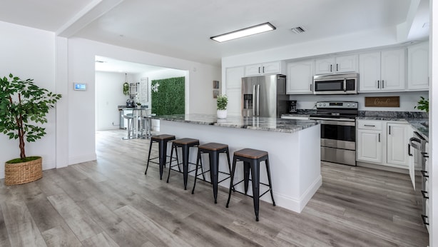 A modern kitchen with white cabinets, stainless steel appliances, and a central island with bar stools.