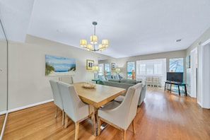 A spacious living room with a wooden dining table, grey sofas, and a TV area. - FREE Seasonal Activities | Private Beach | Chateau La Mer 12B! (Destin)