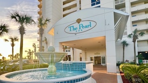 A hotel entrance with a fountain, palm trees, and a sign reading "The Pearl." - Updated 2BR/2BA, 14th Floor, Gulf & Sound Views, Seasonal Beach Service Included (Navarre Beach)