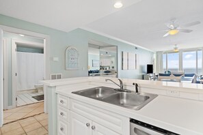 A modern kitchen with white cabinetry, a double sink, and a dishwasher.