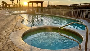 A swimming pool with a sunlit sky, a gazebo, and palm trees. - Updated 2BR/2BA, 14th Floor, Gulf & Sound Views, Seasonal Beach Service Included (Navarre Beach)