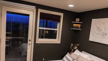 A bedroom with a bed, a window, a door, and a ceiling light.
