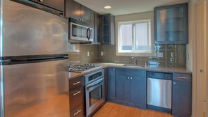 A modern kitchen with stainless steel appliances, dark cabinetry, and a window providing natural light.