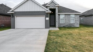 A residential house with a white garage door, a stone facade, and a grey roof. - Upscale in Uptown West 4/2/2 (Lubbock)