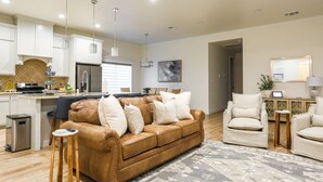 A modern living room with a brown leather sofa, a wooden coffee table, and a patterned rug. - Upscale in Uptown West 4/2/2 (Lubbock)