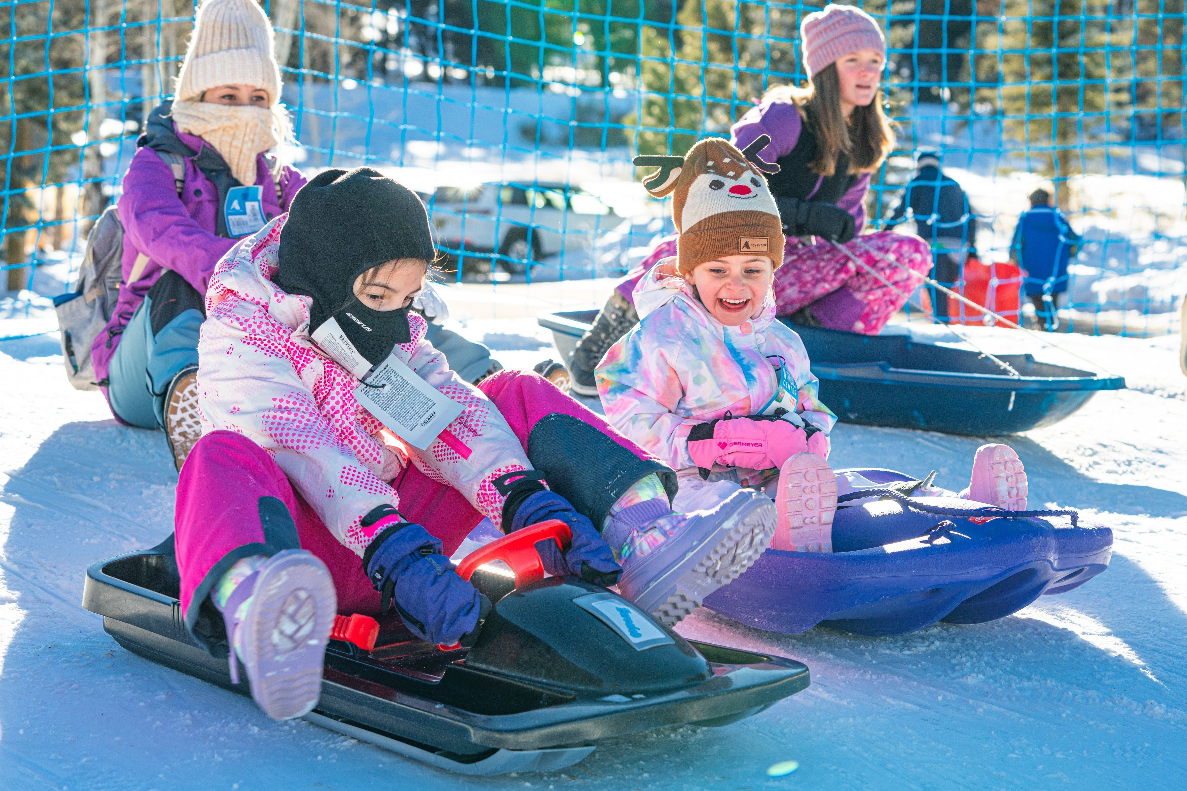 Children sledding on snow-covered ground.