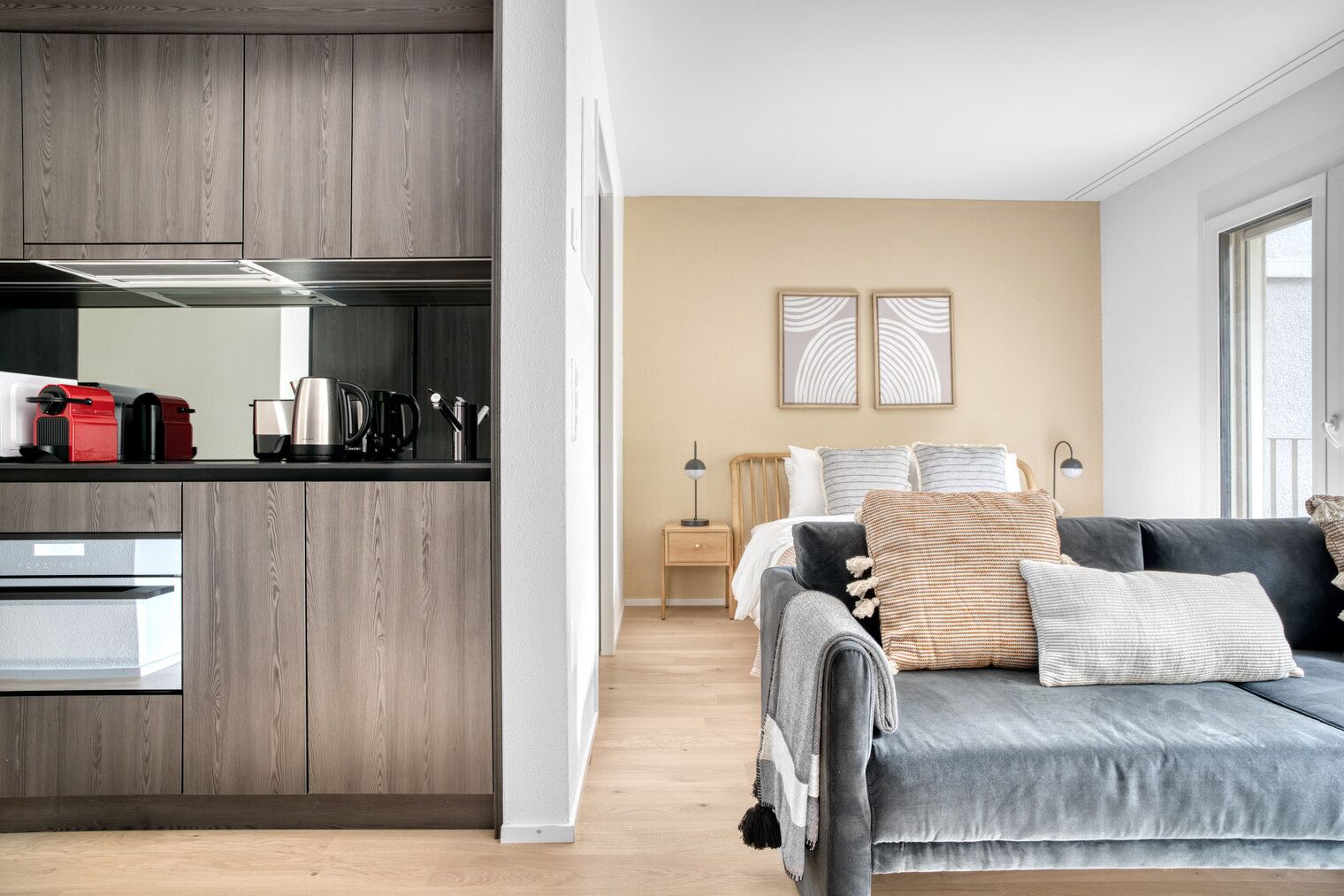 Een moderne keuken met inbouwapparatuur en een gezellige zithoek met een bank en decoratieve kussens.
