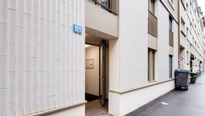 Ein Gebäude mit Schilder mit der Nummer 121, einer Tür und einer Mülltonne am Gehweg.
