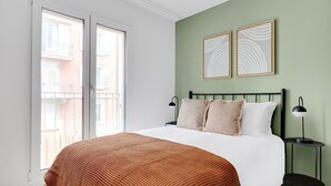 Ein Schlafzimmer mit einem Bett, zwei Nachttischen, einem Fenster und zwei Wandbildern.