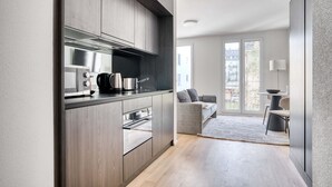 A modern kitchen with dark wood cabinets, stainless steel appliances, and a grey countertop. - Sunlit Wiedikon 1 Room w/ Storage & W/D, 1 min to Market, by Blueground (Zurich)