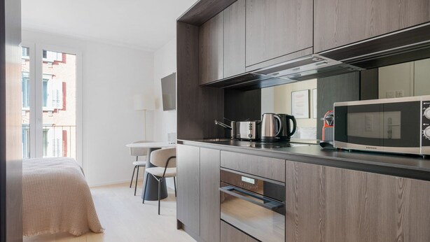 Een moderne keuken met een magnetron, toaster en waterkoker. Er is een eethoek met een tafel en stoelen.