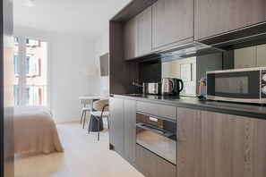 Een moderne keuken met een magnetron, toaster en waterkoker. Er is een eethoek met een tafel en stoelen.