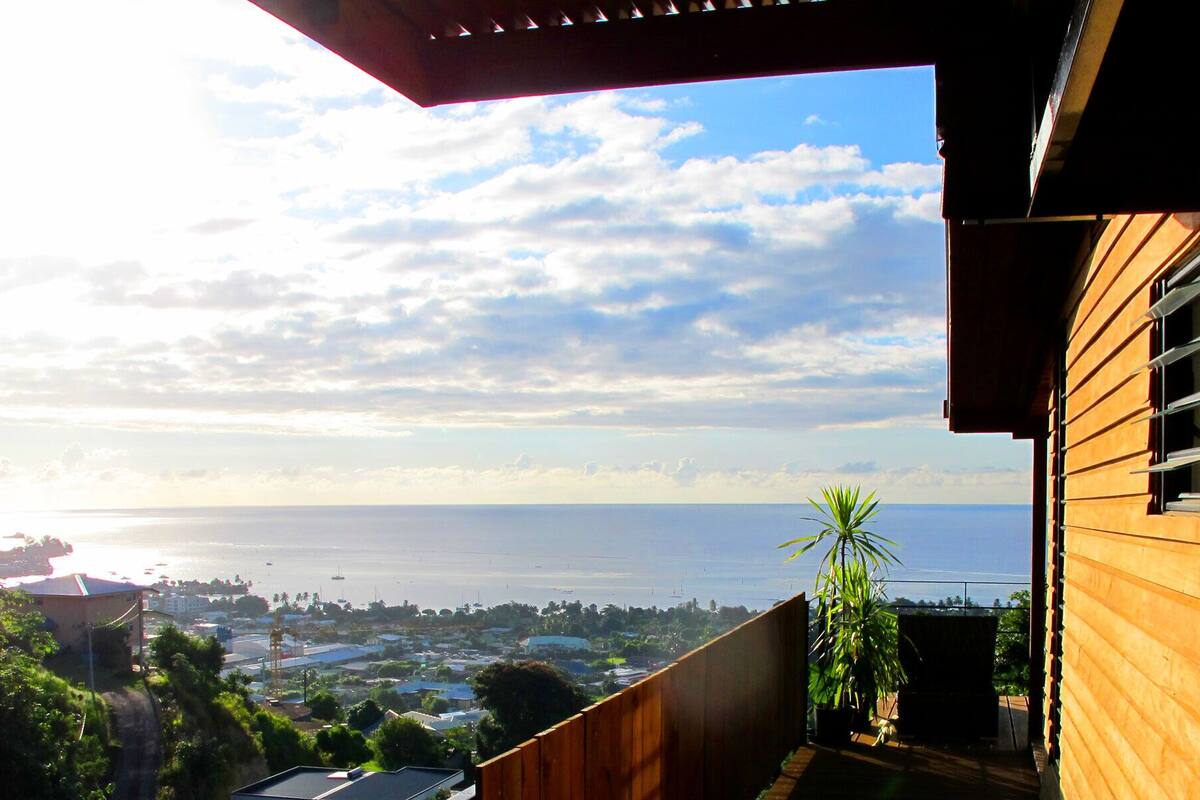 A coastal view from a wooden building with a balcony overlooking a marina and the sea.