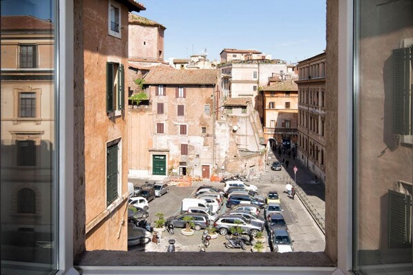 A view of a narrow street with parked cars and buildings.