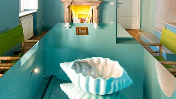A room with a large, uniquely shaped table, a green bench, and a yellow chair. - Ghetto Luxury Design Apartment (Roma)