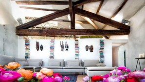 An interior with exposed wooden beams, a sofa, a rug, and a wall with various decorative items. - Ghetto Luxury Design Apartment (Roma)