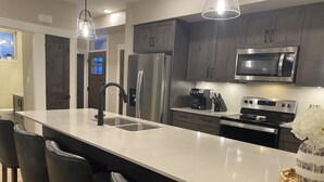 Eine moderne Küche mit dunklen Holzschränken, Edelstahlgeräten und einer zentralen Kochinsel mit Barhocker.