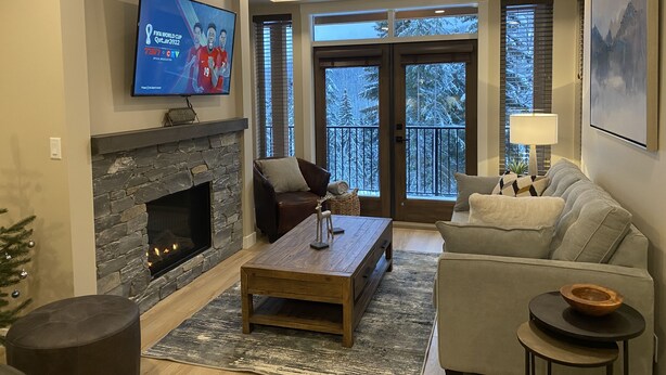 Ein Wohnzimmer mit Kamin aus Stein, einem Flachbildfernseher, einer Couch und einem Couchtisch.