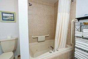 A bathroom with a bathtub, a toilet, a shower curtain, and a towel rack. - Peacefield at The Hilltop Condo (Fish Creek)