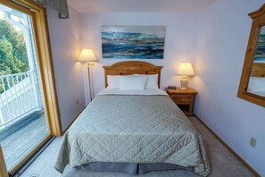 Ein Schlafzimmer mit einem Bett, zwei Nachttischlampen, einem Gemälde, einem Fenster und einem hölzernen Kopfteil.