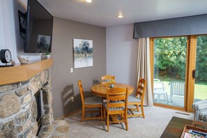 Ein Essbereich mit Kamin aus Stein, einem Flachbildfernseher und einem Gemälde an der Wand.