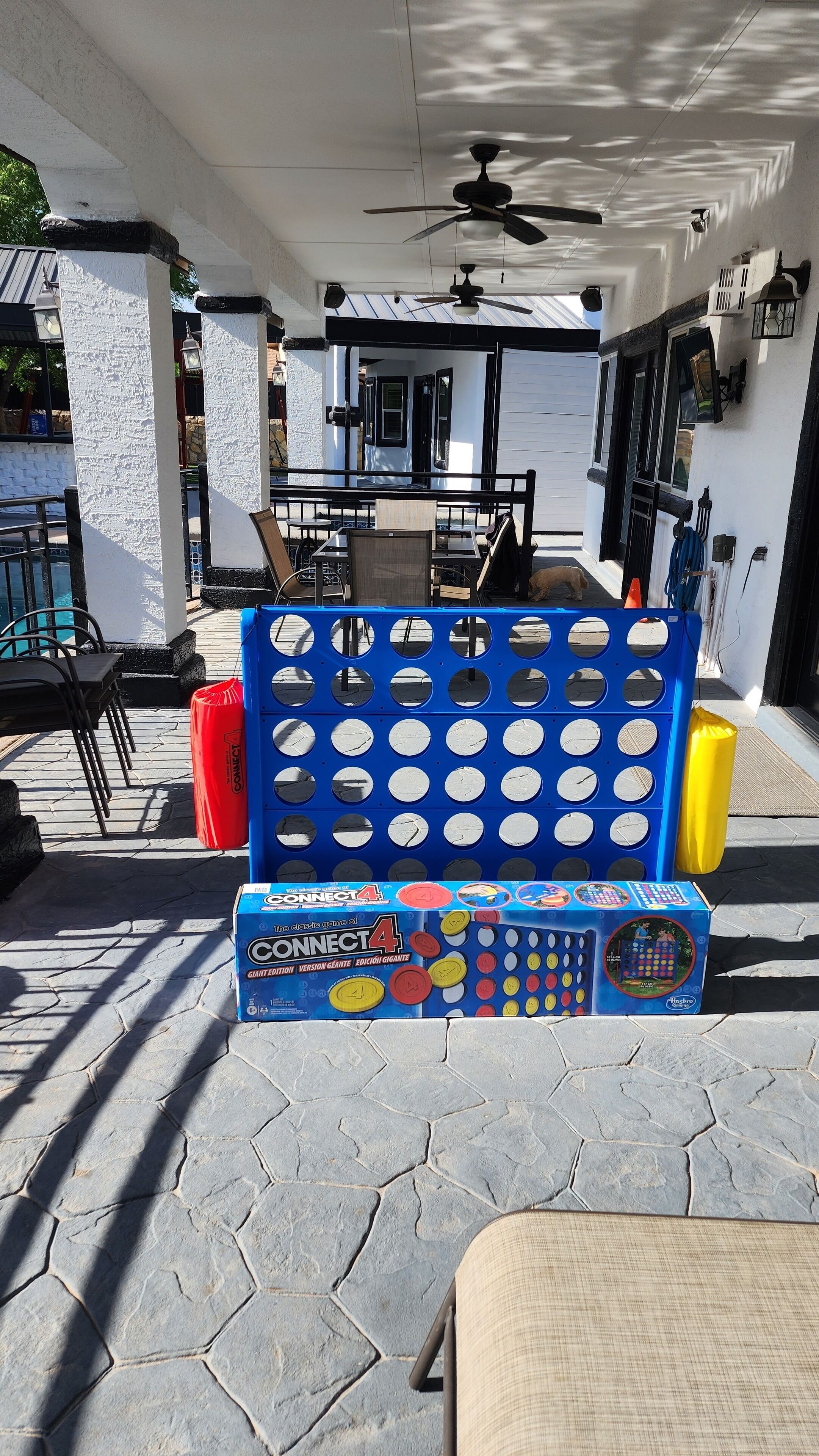 Un patio con un juego de Connect4, mobiliario exterior y un ventilador de techo.