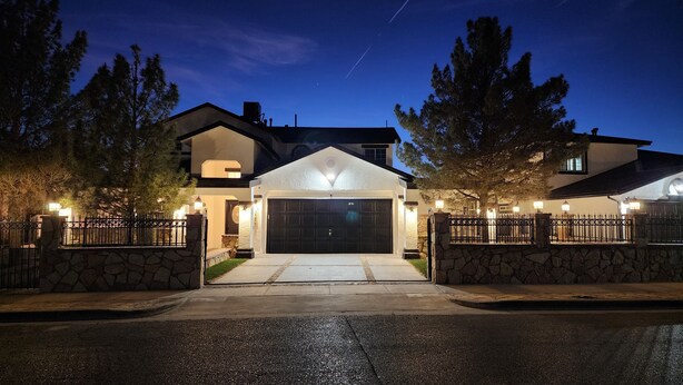 A modern two-story house with a garage, stone walls, and a well-lit driveway. - Swimming pool, 4 bedroom 2.5 bath + bonus room, outdoor dining and outdoor TV  (El Paso)