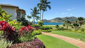 A resort with a well-maintained lawn, palm trees, and a view of the ocean. - Marriott's Kauai Lagoons 3BR Oceanfront Villa (Lihue)