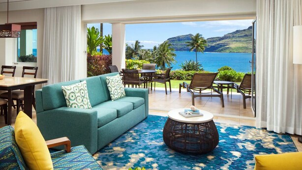 A spacious living room with a sofa, chairs, a coffee table, and a view of the ocean. - Marriott's Kauai Lagoons 3BR Oceanfront Villa (Lihue)