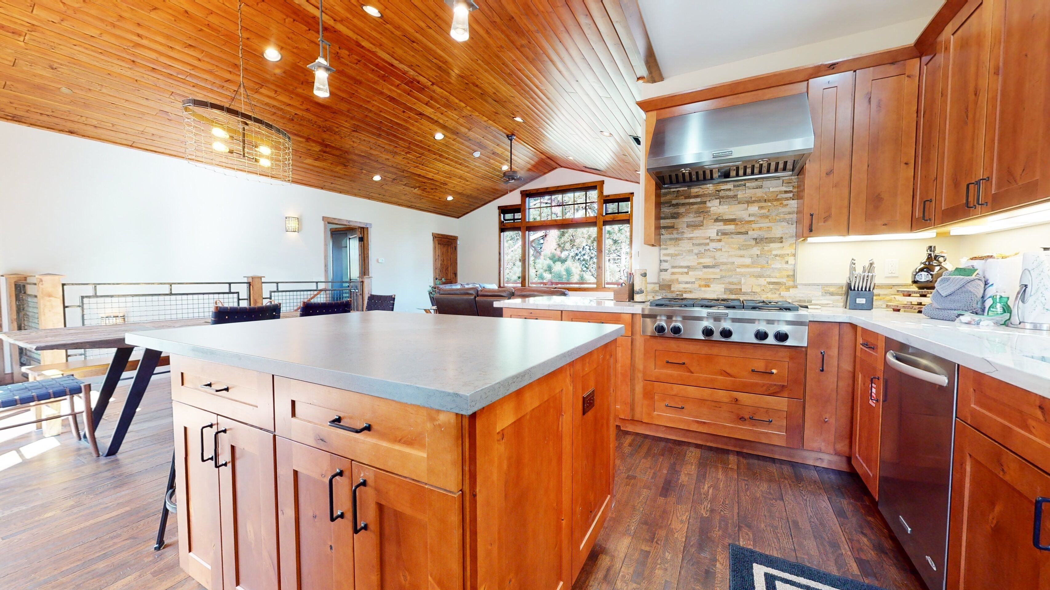 A spacious kitchen with wooden cabinets, a large island, and a stone backsplash.