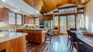 A modern kitchen with wooden cabinets, a stainless steel refrigerator, and a large island. - Graystone #2024 4 Bedroom Home by RedAwning (Mammoth Lakes)