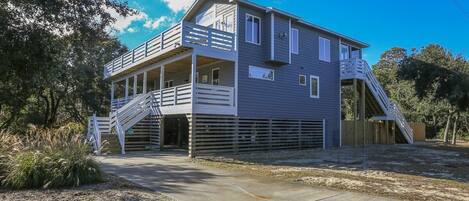 A two-story house with a balcony on the upper floor, a covered driveway, and a fenced yard.