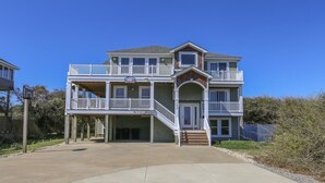 Une maison à deux étages avec un balcon à l’étage supérieur, un porche abrité et un garage.