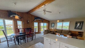 A spacious kitchen with white cabinets, a large island, and a dining area with wooden chairs. - The Dapper Duck - 4 BR Beach Cottage - Dogs Allowed (Southern Shores)