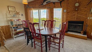 A wooden interior with a round table and chairs, a fireplace, and a view of the outdoors. - The Dapper Duck - 4 BR Beach Cottage - Dogs Allowed (Southern Shores)