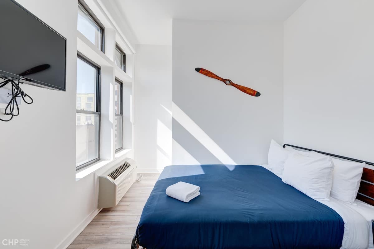 A hotel room with a large bed, a flat-screen TV mounted on the wall, and a ski pole decoration.
