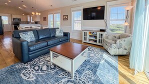 A living room with a sofa, coffee table, TV, and a ceiling fan.