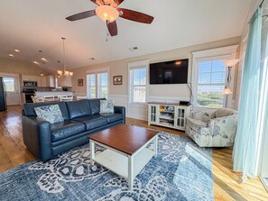 A living room with a sofa, coffee table, TV, and a ceiling fan.