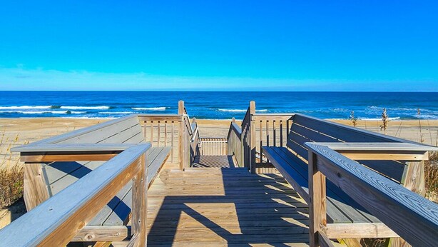 A wooden boardwalk leading to the beach with a clear view of the ocean.