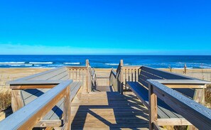A wooden boardwalk leading to the beach with a clear view of the ocean.