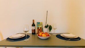 Spisebord med to vinglas, en flaske Terra Lenta vin, en skål med frugt, en potteplante og en bog om Lissabon.