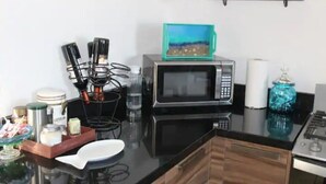 Une cuisine équipée d’un four à micro-ondes, d’une machine à café, d’un grille-pain et d’une étagère avec des bocaux.