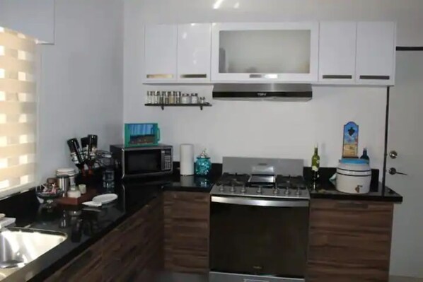 A modern kitchen with a stove, microwave, and cabinets.