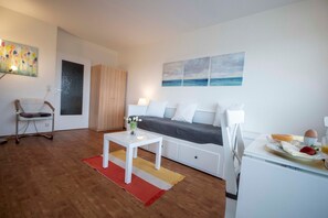 Une chambre moderne et minimaliste, comprenant un lit, une petite table, une chaise et un plateau de petit-déjeuner.