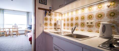 A modern kitchen with a large window, a microwave, a kettle, and a sink.