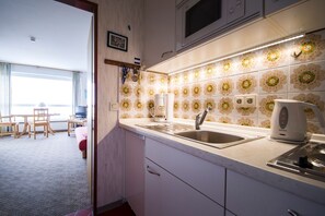 Une cuisine moderne dotée d’une grande fenêtre, d’un four à micro-ondes, d’une bouilloire et d’un évier.