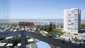 A view of a coastal area with a high-rise building, several smaller buildings, and a marina with boats.