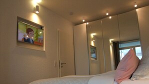 Une chambre à coucher avec un lit, un téléviseur fixé au mur et une fenêtre donnant sur un beau paysage.