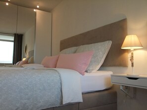 A modern hotel room with a large bed, a bedside table, and a lamp. - FB 05.10 - 4 person vacation apartment with modern furnishings, swimming pool and (Cuxhaven)