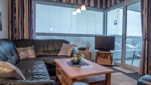 A living room with a leather sofa, a wooden coffee table, and a television on a stand. - FB 03.04 - Strandnahe Gemütliche 2-zimmer Ferienwohnung - Frische Brise (Cuxhaven)